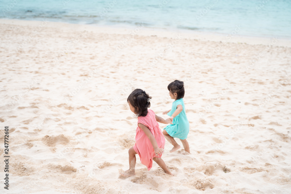 children walking with hold hand together at the white sand seashore