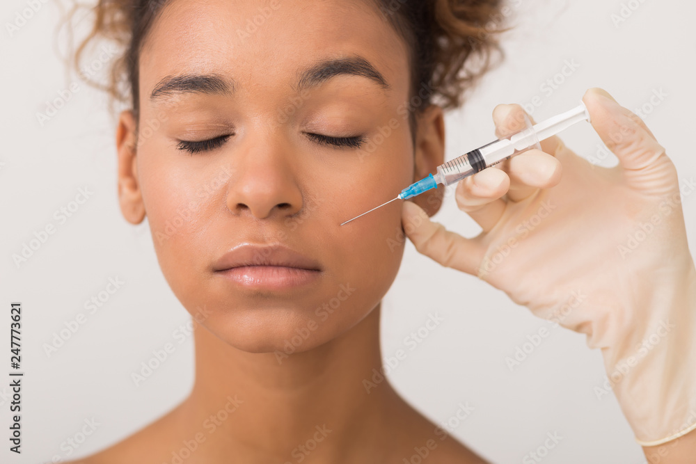 African-american woman getting face injection in clinic African-american woman getting face injection in clinic