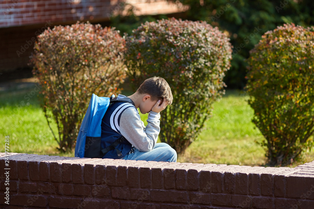 Fototapeta premium Schoolboy crying in the yard of the school