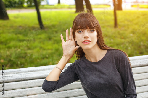 young woman in Park holding a hand near your ear, the concept of eavesdropping