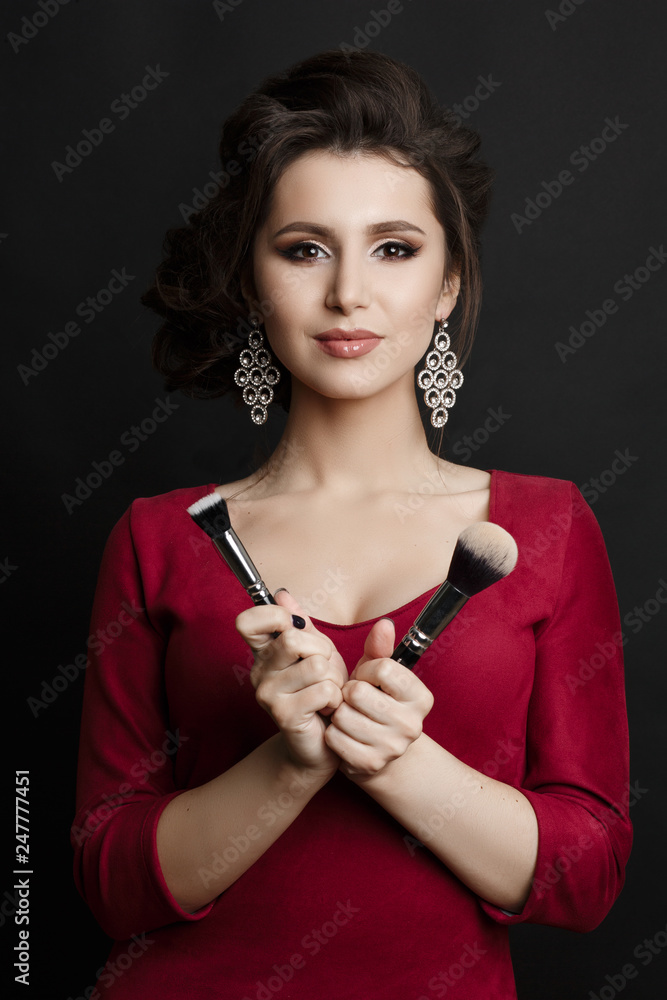 Front view of woman in red dress and big earrings holding makeup