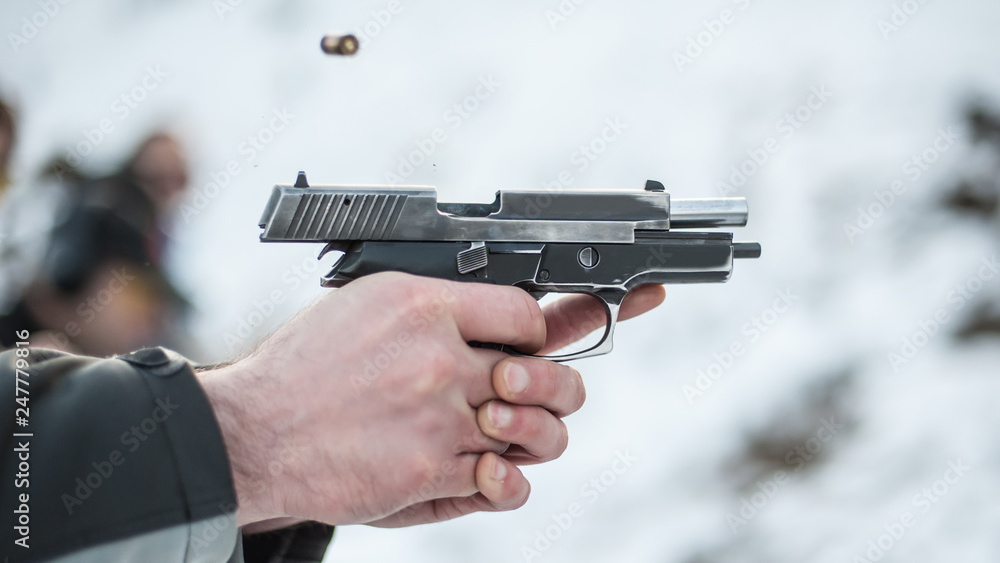 Shooter holding gun in hand and shooting. Close-up detail view Shooter holding gun in hand and shooting. Close-up detail view