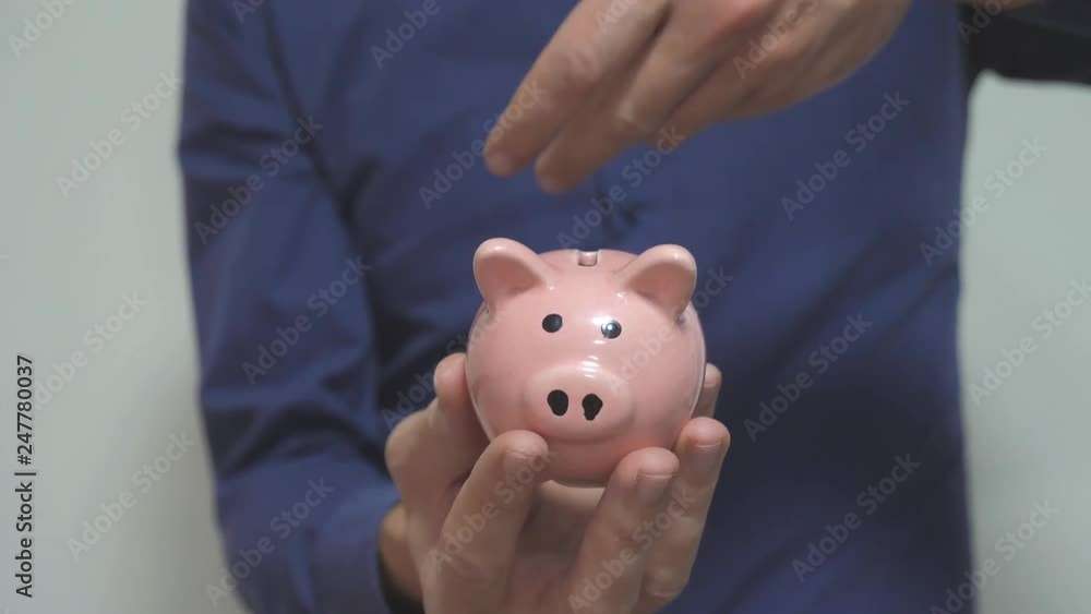 businessman makes savings puts coins in a piggy lifestyle bank. piggy bank business concept. slow motion video. saving money is an investment for the future. Banking investment and finance. hand is businessman makes savings puts coins in a piggy lifestyle bank. piggy bank business concept. slow motion video. saving money is an investment for the future. Banking investment and finance. hand is