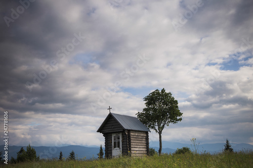 Old weathered small wooden chapel isolated in beautiful countryside landscape. Horizontal color photography.