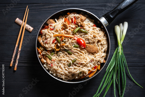 .Thai noodle wok with chopsticks in a frying pan on a black wooden background with a place for copy space