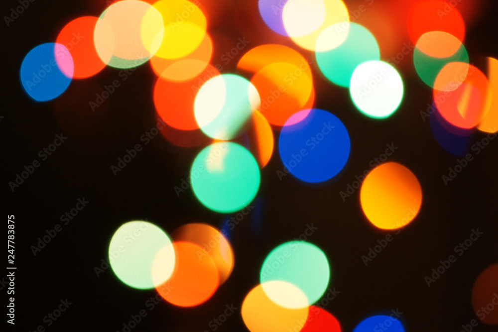Multi-color holiday garland. Garland is blurred. Many colorful round lights. Fully defocused photo. Blurred background and foreground. Holiday mood. New Year and Christmas is coming. Multi-color holiday garland. Garland is blurred. Many colorful round lights. Fully defocused photo. Blurred background and foreground. Holiday mood. New Year and Christmas is coming.