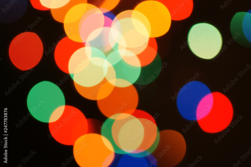 Multi-color holiday garland. Garland is blurred. Many colorful round lights. Fully defocused photo. Blurred background and foreground. Holiday mood. New Year and Christmas is coming. Multi-color holiday garland. Garland is blurred. Many colorful round lights. Fully defocused photo. Blurred background and foreground. Holiday mood. New Year and Christmas is coming.