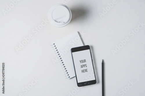 Mobile phone, notebook and coffee on a pale background