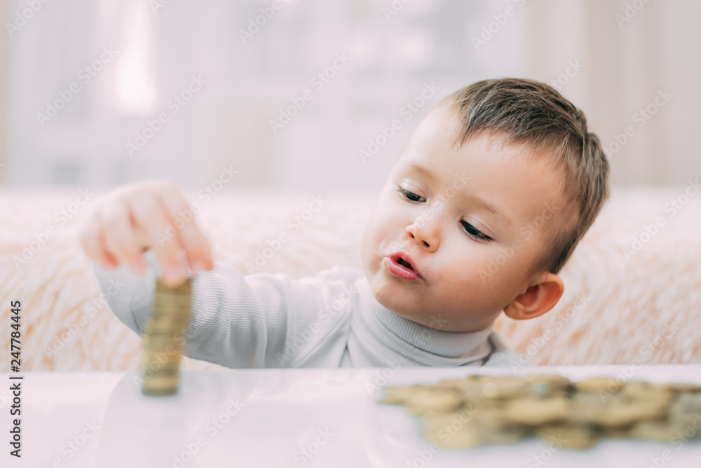 Fototapeta premium The child builds the tower of the coins closeup