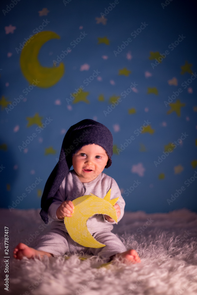 Little baby boy with cute teddy bear and moon on a blue star and moon background