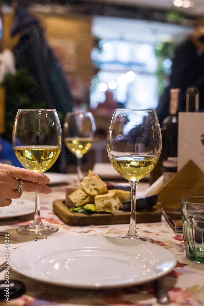 White wine in glasses on a table in a restaurant where a group of friends or family is having dinner