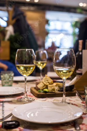 White wine in glasses on a table in a restaurant where a group of friends or family is having dinner