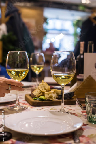 White wine in glasses on a table in a restaurant where a group of friends or family is having dinner