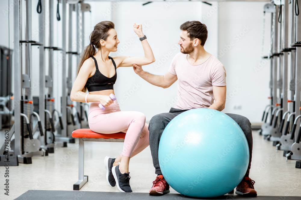 Obraz premium Portrait of a young sports couple sitting with fitness ball during the break at the rehabilitation gym