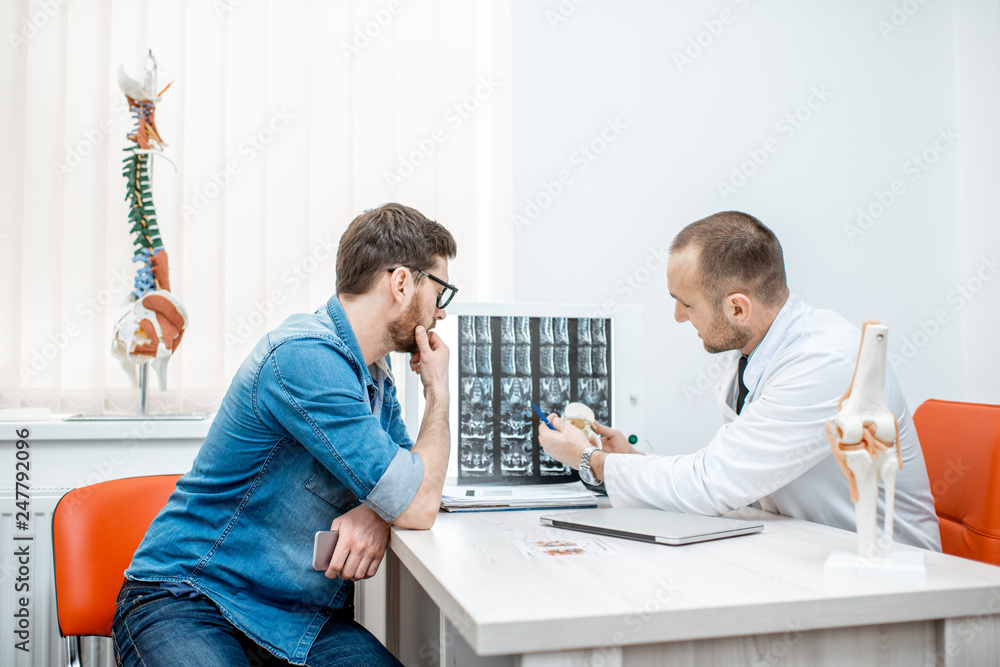 Obraz premium Man during the medical consultation with senior therapist looking on the tomography print at the office