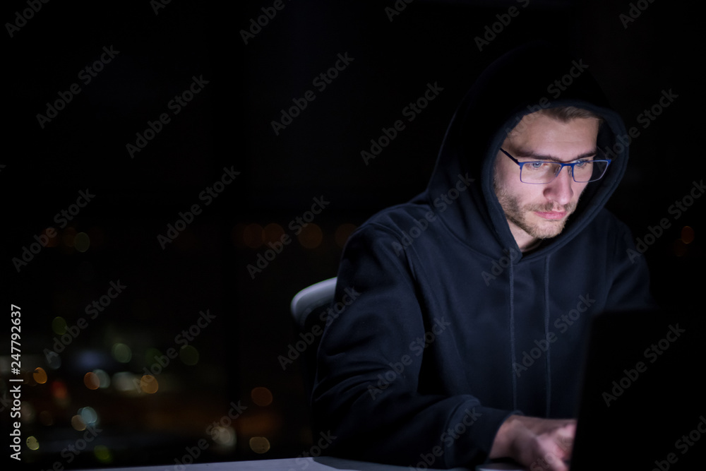 hacker using laptop computer while working in dark office hacker using laptop computer while working in dark office