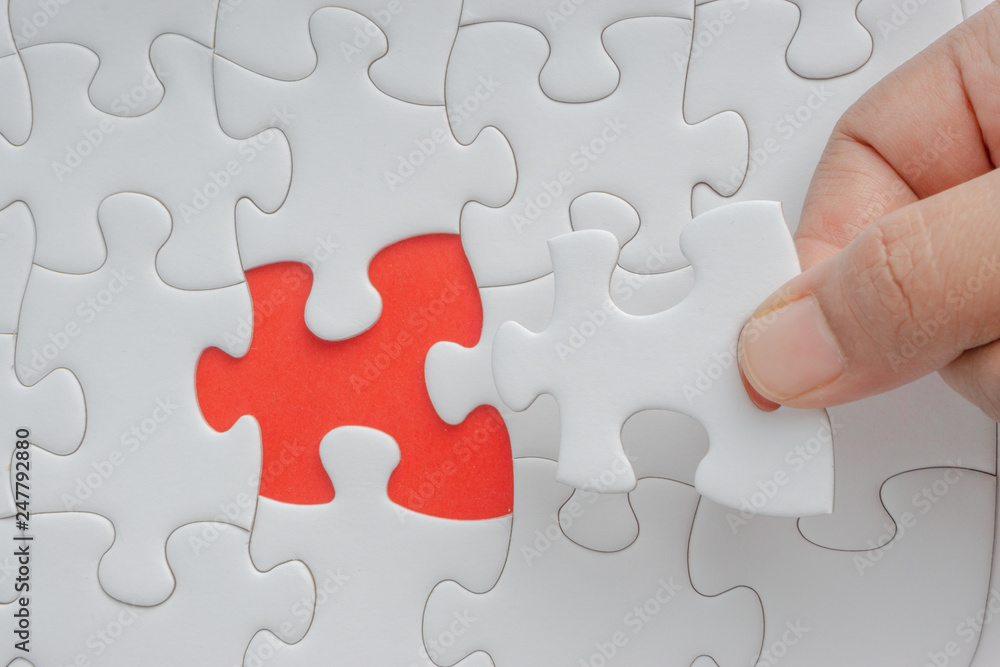 Hand put the last piece of jigsaw puzzle closeup to complete the mission. Selective focus and crop fragment Hand put the last piece of jigsaw puzzle closeup to complete the mission. Selective focus and crop fragment
