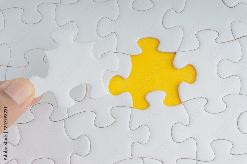 Hand put the last piece of jigsaw puzzle closeup to complete the mission. Selective focus and crop fragment Hand put the last piece of jigsaw puzzle closeup to complete the mission. Selective focus and crop fragment