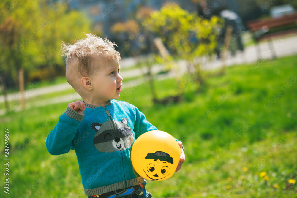 Little boy plays ball. Child on background of grass and trees. Little boy plays ball. Child on background of grass and trees.