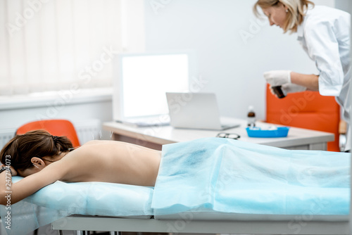 Neuropathologist puts needles into the woman s back removing inflammation of the muscles during the acupuncture treatment in the office