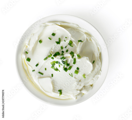 Cream cheese, quark or yogurt in a white bowl. Dairy product with fresh herbs, healthy eating theme. Isolated object on white background.