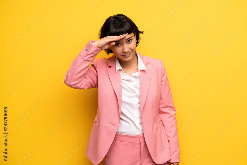 Modern woman with pink business suit looking far away with hand to look something Modern woman with pink business suit looking far away with hand to look something