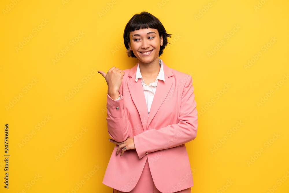 Modern woman with pink business suit pointing to the side to present a product Modern woman with pink business suit pointing to the side to present a product