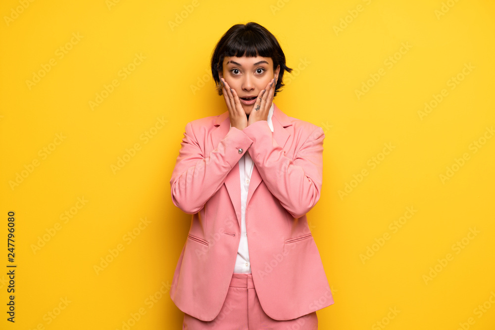 Modern woman with pink business suit surprised and shocked while looking right Modern woman with pink business suit surprised and shocked while looking right