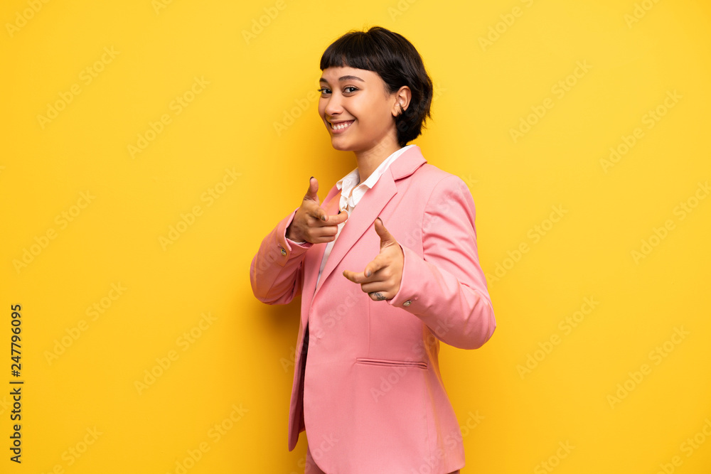 Modern woman with pink business suit pointing to the front and smiling Modern woman with pink business suit pointing to the front and smiling