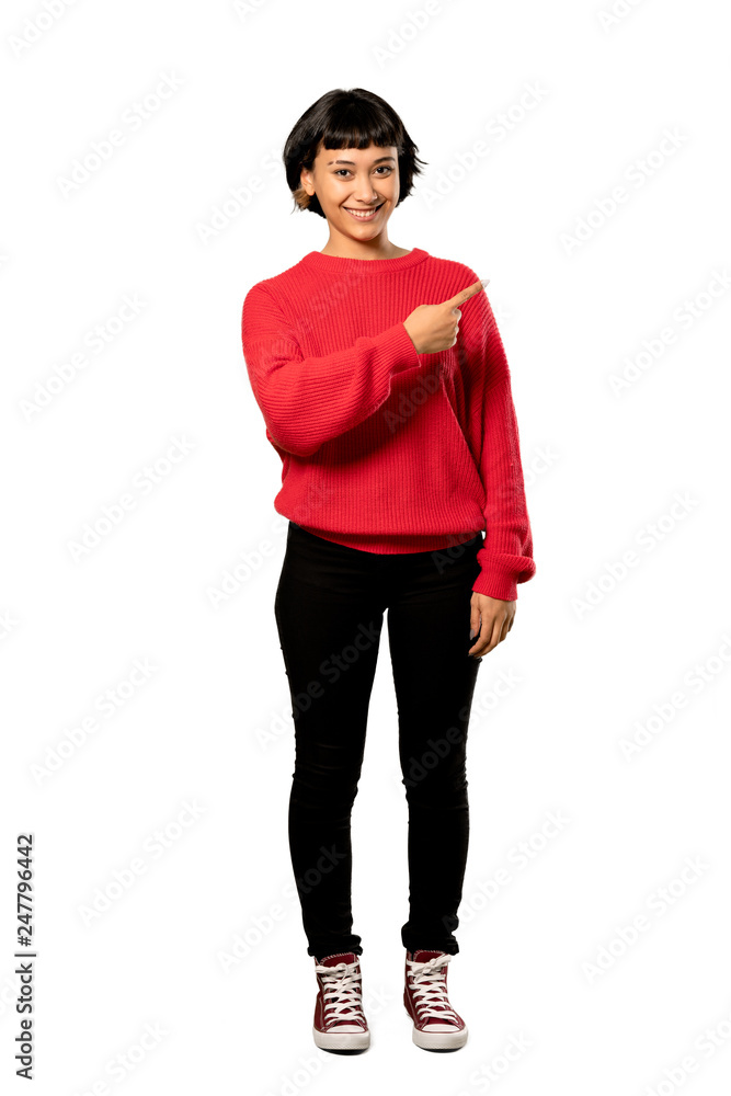 Fototapeta premium A full-length shot of a Short hair girl with red sweater pointing to the side to present a product over isolated white background