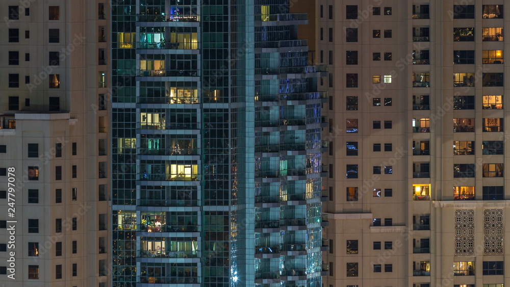 Glowing windows in multistory modern glass residential building light up at night timelapse. Glowing windows in multistory modern glass residential building light up at night timelapse.