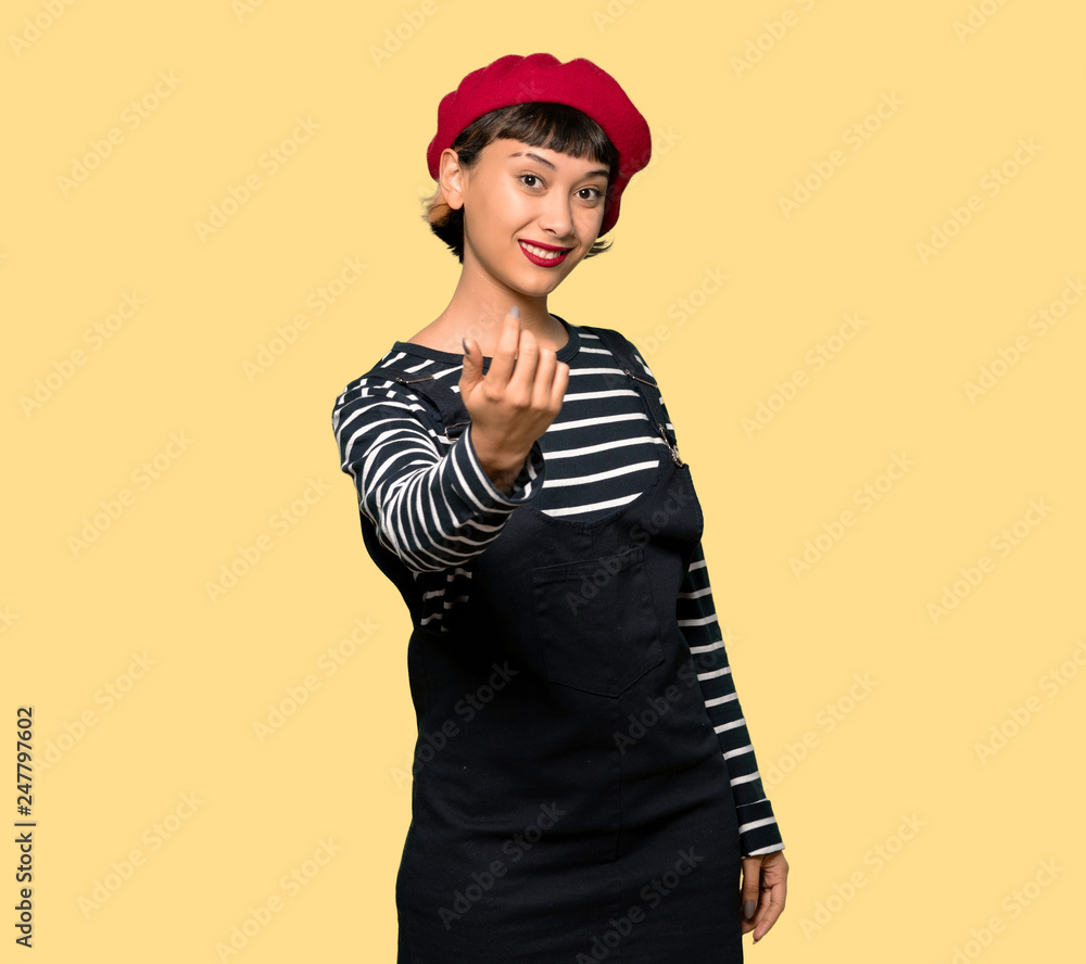 Young woman with beret inviting to come with hand. Happy that you came over yellow background Young woman with beret inviting to come with hand. Happy that you came over yellow background