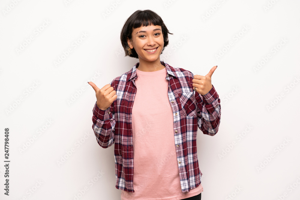 Young woman with short hair giving a thumbs up gesture with both hands and smiling Young woman with short hair giving a thumbs up gesture with both hands and smiling