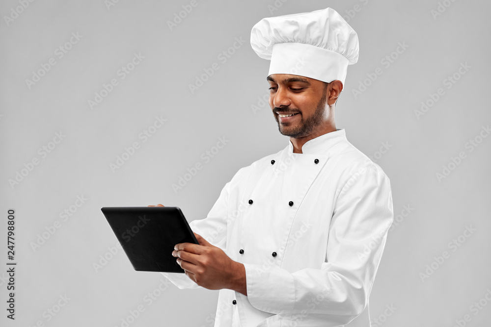 cooking, technology and people concept - happy male indian chef in toque with tablet computer over grey background cooking, technology and people concept - happy male indian chef in toque with tablet computer over grey background