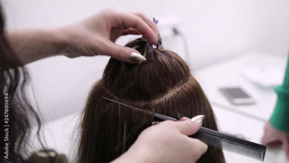 Hairdresser hair styling client in a beauty salon. Hairdresser combing her dark hair with a comb to client in Barber shop close-up Hairdresser hair styling client in a beauty salon. Hairdresser combing her dark hair with a comb to client in Barber shop close-up