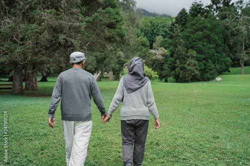 portrait of asian muslim senior couple walking in the garden together