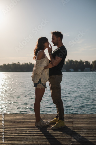 Man touching his smiling girlfriend nose by the river