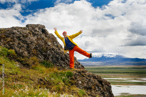 Happy young woman in bright clothes traveling Iceland, enjouing nature photo