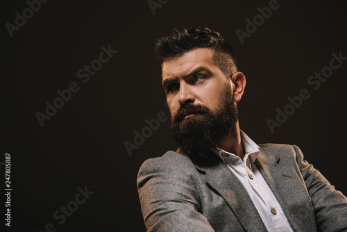 Fototapeta Naklejka Na Ścianę i Meble -  handsome thoughtful businessman looking away isolated on brown