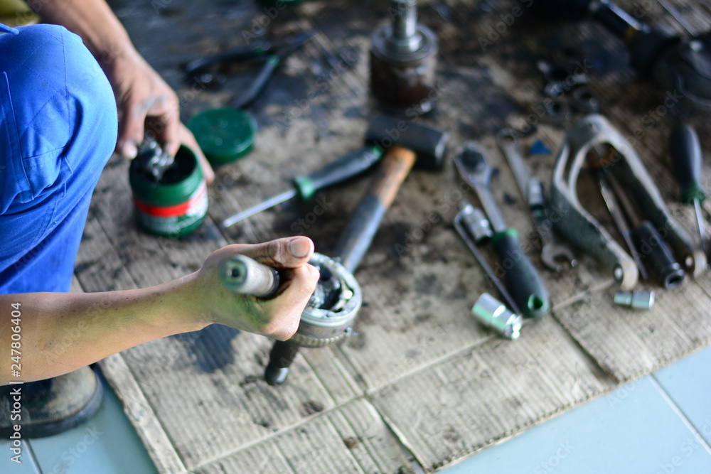 the blur of mechanic holding a car part l and apply grease into the part the blur of mechanic holding a car part l and apply grease into the part