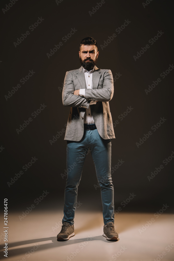 handsome businessman standing with crossed arms on brown handsome businessman standing with crossed arms on brown