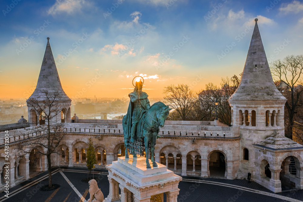 Fototapeta premium Budapeszt, Węgry - Widok z lotu ptaka na wieże słynnego Baszty Rybackiej (Halaszbastya) z pomnikiem króla Stefana I o wschodzie słońca