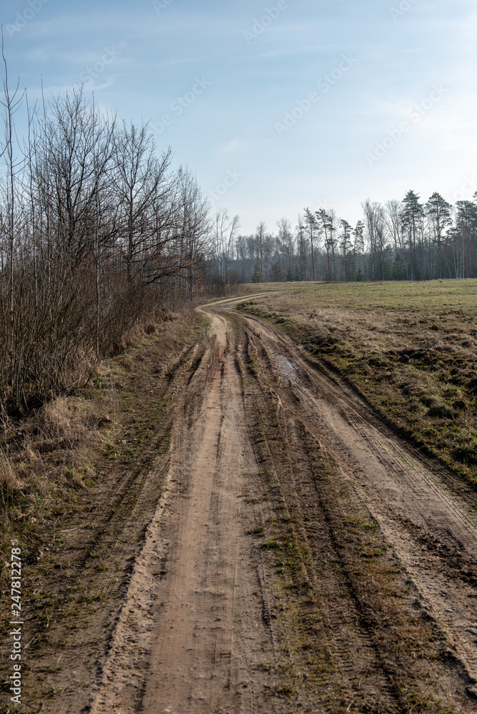 empty country gravel road with mud puddles and bumps