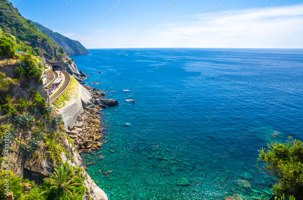 Aerial top panoramic view of Ligurian Sea and Manarola train station, coastline with rocks and cliffs of Riviera di Levante, National park Cinque Terre, blue sky copy space, La Spezia, Liguria, Italy
