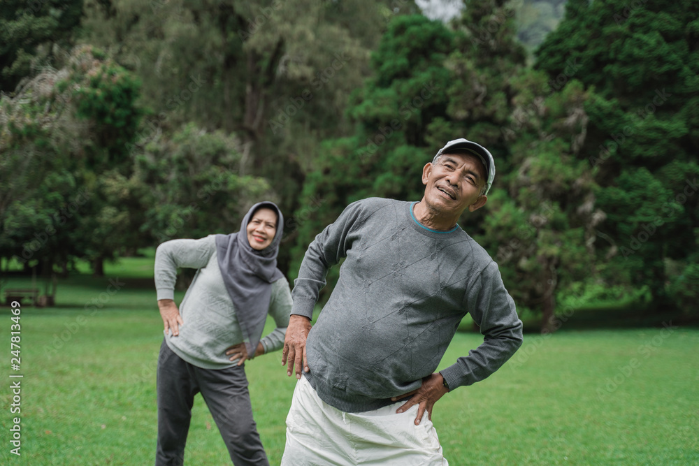 two senior man and woman doing some stretching in nature park together. old people healthcare by doing sport