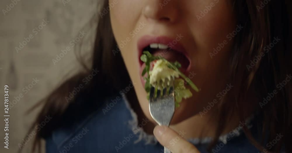 An attractive, young woman enjoys eating a healthy sandwich and salad for lunch. Shot in slow motion