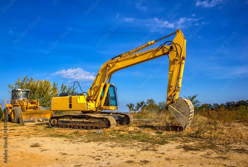 Day view of yellow bulldozer and excavator with a shovel after work. Day view of yellow bulldozer and excavator with a shovel after work.