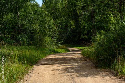 empty country gravel road with mud puddles and bumps