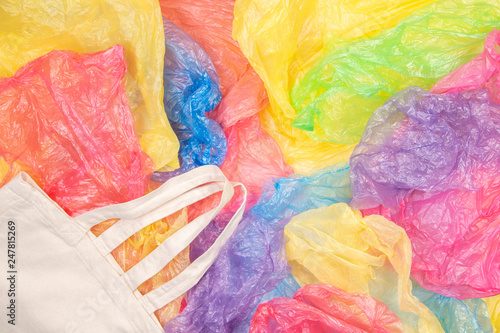 Wallpaper Mural Many multicolored plastic bags with one eco natural reusable shopping bag background. Zero waste, eco friendly, sustainability lifestyle, no plastic concept Torontodigital.ca