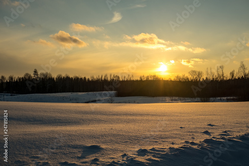 colorful sunset in winter over countryside fields covered in snow